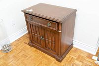 Front angle view of the mahogany buffet cabinet showing the top and front with one drawer and two doors with carved wood details and brass handles.