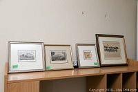 Four framed artworks on a shelf, showing various sizes and frame styles.