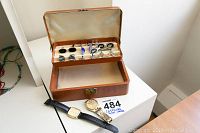 Image showing open brown leather jewelry box with eight pairs of cuff links inside, two men's watches outside, one with leather strap and one with metal band