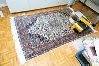 Full view of rectangular rug on parquet floor with storage boxes on top