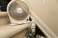 White Airworks tabletop fan and Black & Decker steam iron placed on carpeted stairs