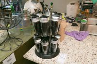 Full view of the double revolving spice rack with 12 spice jars, placed on a kitchen counter among other household items.