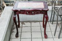 Front view of the wood table showing carved legs and stone top.