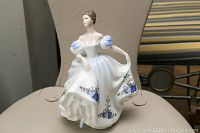 Front view of the Royal Doulton Beatrice figurine featuring the detailed face, blue floral decorated dress, and puffed sleeves.
