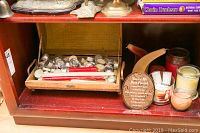 Wooden decor trunk partially open sitting on red shelf with assorted candles and plaque around it.