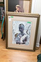 Full view of the framed art print showing the woman portrait and part of surrounding artworks and floor