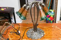 Full view of the lamp showing the metal arms, floral glass shades, and part of the cord.
