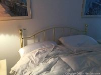 Full queen bed setup with brass headboard, white comforter and pillows.