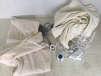 Two folded queen size electric blankets in beige and cream colors with multiple cords and remote controls on floor.