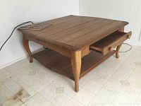 Photo showing front and side view of vintage pine coffee table with the storage drawer partially opened and visible lower shelf.