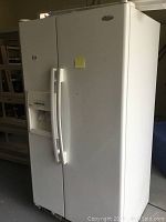 Front view of white Whirlpool side-by-side refrigerator showing two doors and integrated ice and water dispenser on left door.