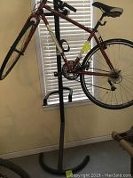Red James bike mounted on the vertical bike rack in a room with window blinds, showing front profile and frame.