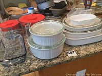 Overview of all items showing CorningWare casserole dishes, Pyrex measuring cups with lids, and bakeware items on the kitchen counter.