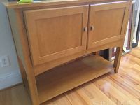 Front angle showing wooden entry table with two cabinet doors and open lower shelf