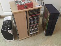 Wooden CD carousel rack filled with around 100 CDs, boxed DVD player, boxed Far Side CD collection, black and white box for CD storage, and another boxed set.