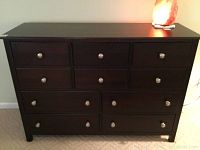 Full front view of the chest of drawers showing 10 drawers with brushed nickel pulls and the merlot stained wood finish