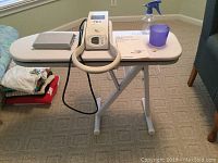 Full view of steam press setup on stand showing pressing surfaces and accessories on tabletop