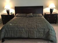 Full view of king size bed frame with comforter, pillows and nightstands