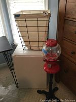 Photo showing all three items together: laundry basket on mini fridge, gumball machine on black stand next to fridge