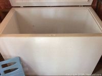 White Frigidaire Gallery chest deep freezer with the lid open showing the interior interior wall and top edge.