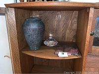 Shelf with the urn, glass paperweight, and stone piece arranged together.