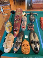 Top-down photo of nine masks arranged on a pool table showing variety of colors and styles.