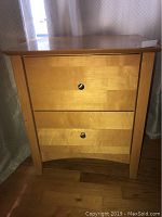 Front angle of the maple wood nightstand showing two drawers and curved legs.