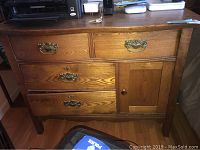 Front view of vintage style oak nightstand showing four drawers and one cubby compartment with ornate brass-tone handles and wooden knob.