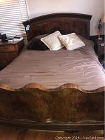 Full view of queen bed set with mattress and pillows, showing carved wood headboard and footboard with dark finish.