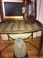 Rolling cart with woven top shelf and metal frame seen from angle, King Tut bust on lower shelf, Santa Fe lantern on top