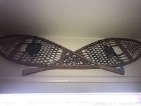 Pair of vintage wooden snow shoes arranged crossed on a wall.