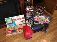 Photo showing two Monopoly board games, a red Everlast boxing glove, a black resistance band, and stacks of DVDs.