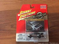 Johnny Lightning Classic Car 1982 Porsche 911 Turbo die cast car in original sealed packaging, metallic silver color with black detailing.