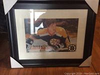 Front view of framed photograph showing Bobby Orr in Boston Bruins uniform within black frame and white mat board