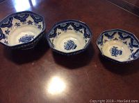 Three vintage Makkum Delft pottery bowls arranged on table showing different sizes and blue and white floral designs.