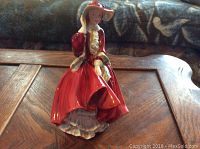 Side angled view of the Royal Doulton figurine in a red dress showing overall detailing and condition.