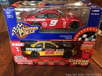 Photo showing both die cast cars in original packaging placed side by side on wood surface, highlighting branding and box condition.