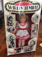 Front view of original box with Shirley Temple doll in white and red dress visible inside. Box shows creasing and wear.