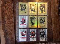 Nine Tim Hortons hockey cards in a plastic sheet protector on a wooden table, showing front sides with player images and holographic foiling.