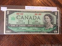 Front side of the 1967 Canadian Centennial one dollar bill showing the portrait of Queen Elizabeth II and the Centennial logo.