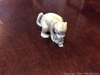 Photo of the carved bone netsuke of a monkey holding a smaller monkey, showing detailed carving and natural bone coloration.