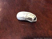 Photo of the side view of the small bone carved netsuke showing detailed carving and discoloration.