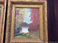 Photo of first vintage framed painting showing a lakeside landscape with red and yellow trees, signed by artist Jenkinson, in an ornate gold frame with a chip in the top left corner.
