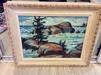 Frontal view of the entire framed painting showing rocky coastline scene with waves and pine trees.