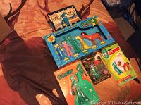 Photo showing 6 Gumby themed collectible sets and figures on a brown background including Gumby's Circus boxed set and single packaged figures.