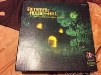 Front of the game box showing the title Betrayal At House On The Hill with haunted house artwork, recommended age 12+, 3-6 players, playtime 1 hour.