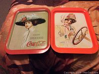Front view of two Coca-Cola trays with vintage women's images and red borders.
