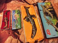 Photo of two decorative knives in original boxes: a dragon dagger and an alligator-shaped knife.