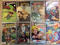 Photo showing 8 Supergirl comic books in a row, each in protective bags and boards, with colorful covers depicting Supergirl in various scenes and themes.