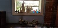 Group of 23 figurines displayed on window sill and table showing ceramic, clay, and glass bird and human figures with a paper rickshaw on table in front.